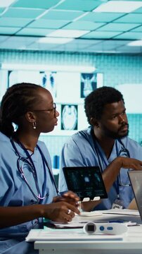Vertical video African american general practitioner leading a healthcare team in a cabinet, analyzing MRI imaging results and providing accurate diagnosis and effective treatment. Medical facility