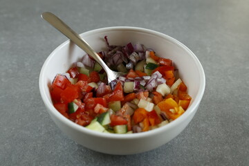 diced vegetable salad in bowl with a spoon