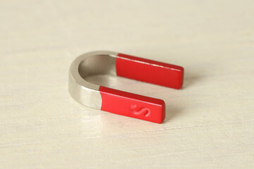 One horseshoe magnet on white wooden table, closeup