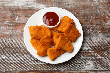 Delicious chicken nuggets with ketchup on wooden table, top view