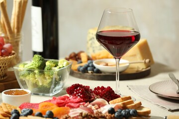 Red wine and different snacks served on table, closeup