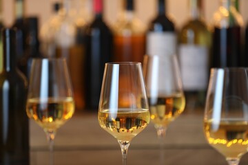 Tasty white wine in glasses against blurred background with festive lights, closeup. Bokeh effect