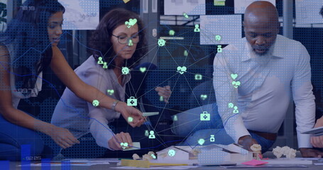 Image of network of connections with icons over diverse colleagues brainstorming in office