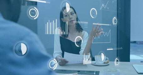 Image of charts processing data over biracial businesswoman talking at casual office meeting