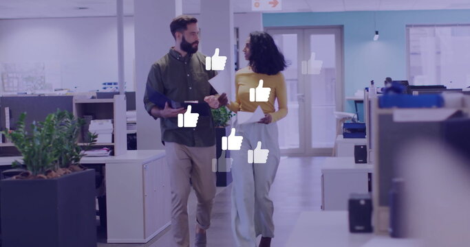 Image of network of thumbs up icons over diverse business people in office