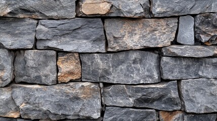 Obraz premium Close-up of a rustic stone wall with dark gray and tan rectangular stones.