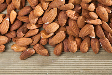 Closeup of shelled roasted almonds on wooden background. Concept of healthy and nutritious food