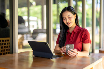 A woman is sitting at a table with a laptop and a cell phone