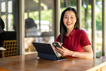 A woman is sitting at a table with a laptop and a cell phone