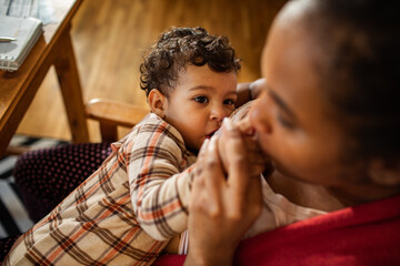 Mother multitasking work and childcare at kitchen table