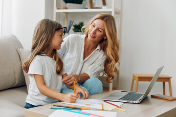 Mother and daughter enjoying quality time on the couch with laptop and colorful pencils for creative learning