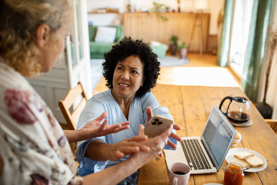 Lesbian couple arguing about cheating at the kitchen table