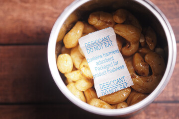 A container filled with cashew nuts accompanied by a desiccant pack