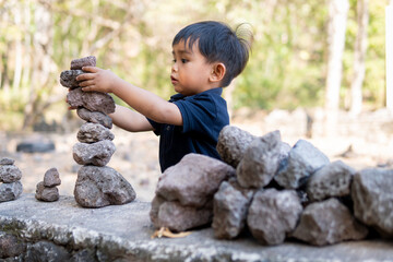 Close up little boy stacking stones balance