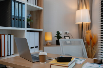 A sunlit office desk with an open laptop, productive workspace environment, cozy office with a stylish wooden desk, modern office space and professional work environment.