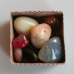 a box of abstract colorful pebbles that are shiny and smooth. special collection of rocks isolated...