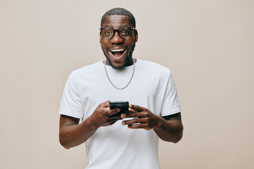 Happy young man using smartphone against a neutral background, showcasing excitement and joy...