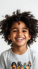 34. A boy smiling brightly, wearing a graphic t-shirt, in front of white