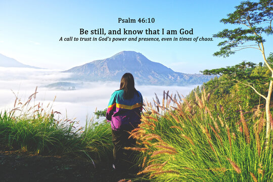 Bible verse quote - Be still, and know that I am God. Psalm 46:10 With woman standing alone between the green tall grass on mountains background with morning light and fog. Christianity. 