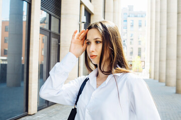 Fashionable woman in the city. Young female model with long hair wears white shirt.