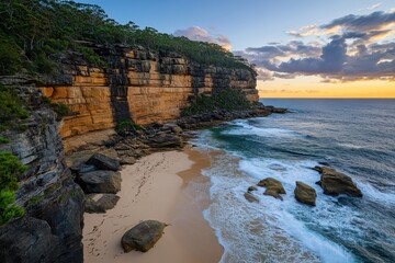 Obraz premium Serene Coastal Landscape at Sunset with Rocky Cliffs and Gentle Waves Reflecting Golden Light on a Tranquil Beach in Australia