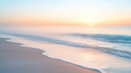 Obraz premium Beach at sunrise with gentle waves and soft mist