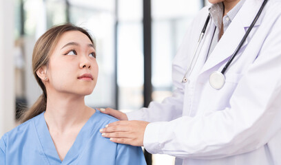 A female patient looks anxious as she listens to a doctor explain her symptoms at hospital.