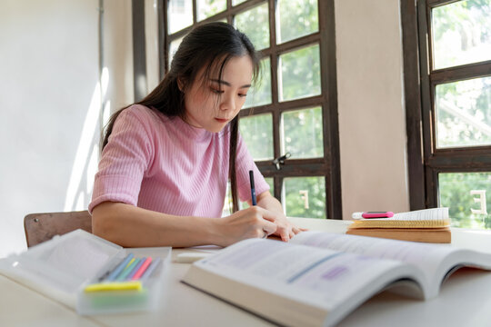 Asian girl student doing exam hand holding pencil writing answer in university classroom education high school or university student taking notes while preparing for exam - Powered by Adobe