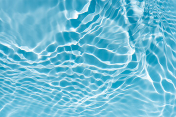Blue water with ripples on the surface. Defocus blurred transparent blue colored clear calm water surface texture with splashes and bubbles. Water waves with shining pattern texture background.