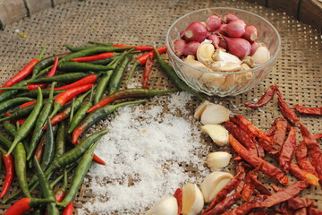 Group of seasoning including hot chili peppers onion, and garlic. laying on the glass of the basket.