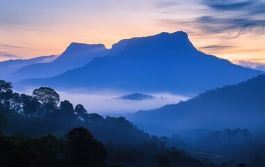 Obraz premium Misty Mountain Range at Dusk with Silhouette Peaks and Pastel Sky.