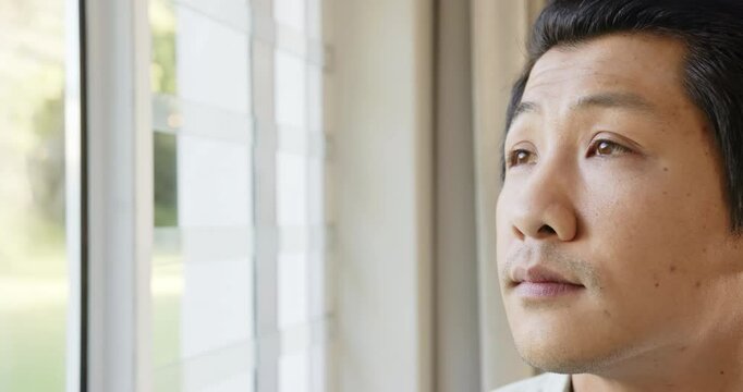 Reflecting and contemplating, asian man looking out window, close-up portrait, copy space