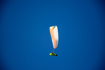 A man with a paraglider in front of a blue sky.