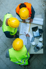 Workers looking at construction plans, view from above
