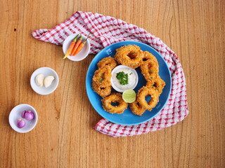 Top View of Crispy Onion Rings with Dipping Sauce on Blue Plate