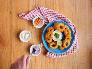 Golden Crispy Onion Rings with Dipping Sauce and Fresh Ingredients on Wooden Table