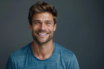 Obraz premium Close up portrait of smiling handsome guy in blue t shirt isolated on gray background