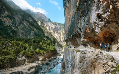 Group of tourists walking along mountain river through narrow gorge enjoying scenic view and active recreation together in Himalayan mountains, Nepal.