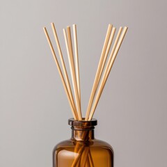 reed diffuser sticks in a brown glass bottle against a gray background