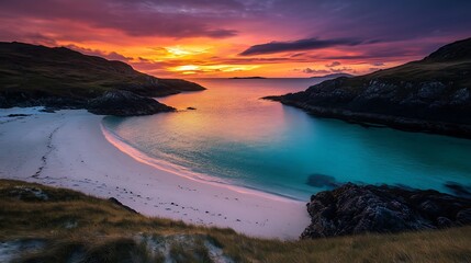 Vibrant sunset over a secluded cove with white sand beach and turquoise water.