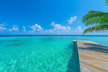 Fototapeta premium Wooden pier extending into crystal-clear turquoise water under a sunny sky, embodying the serenity of a tropical paradise