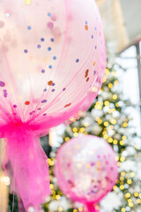Large pink balloons filled with confetti for holiday party.