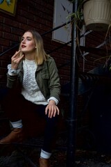 Woman sitting on steps in stylish outfit  in urban setting