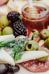 Close-up of olives, salami, cheese, blackberries, and honey