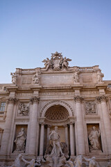The upper facade of the Trevi Fountain under a clear blue sky