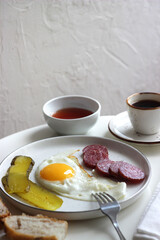 Scrambled eggs, smoked sausage and pickles in a plate on the table.