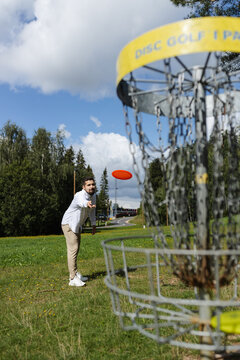 Handsome young adult man playing disc golf on a sunny day