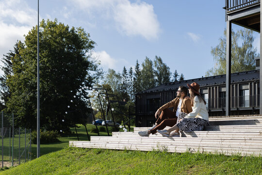 Couple sitting outside on a terrace wooden stair and looking away