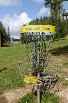 Closeup view of disc golf basket with discs on sunny day