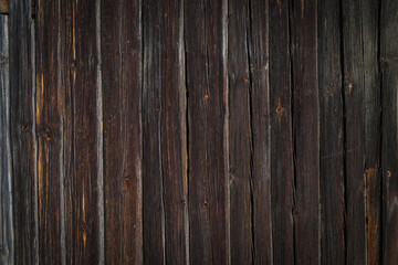 Dark wooden wall of a country house with vertical boards.